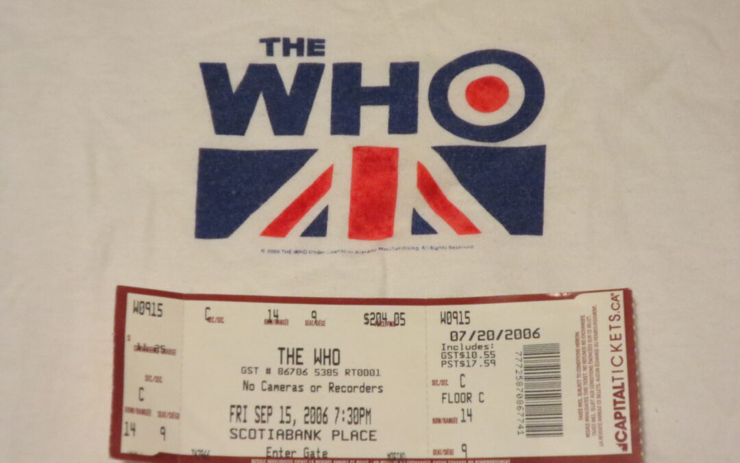 White t-shirt with a stylized royal blue "The Who" written on it. Beneath it is half of the Union Jack, the United Kingdom flag. Below the band name is a ticket stub from the concert at Scotiabank Place.